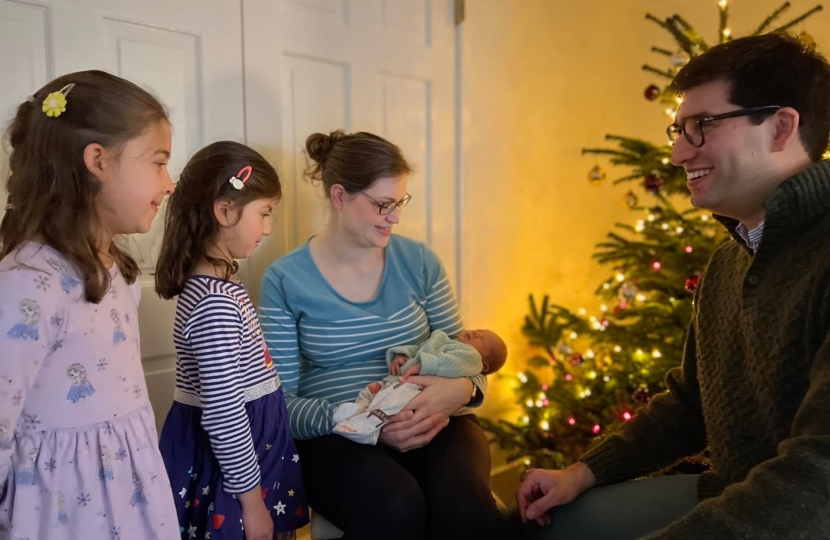 Ranil and Alison with two daughters and new baby boy in front of a Christmas tree