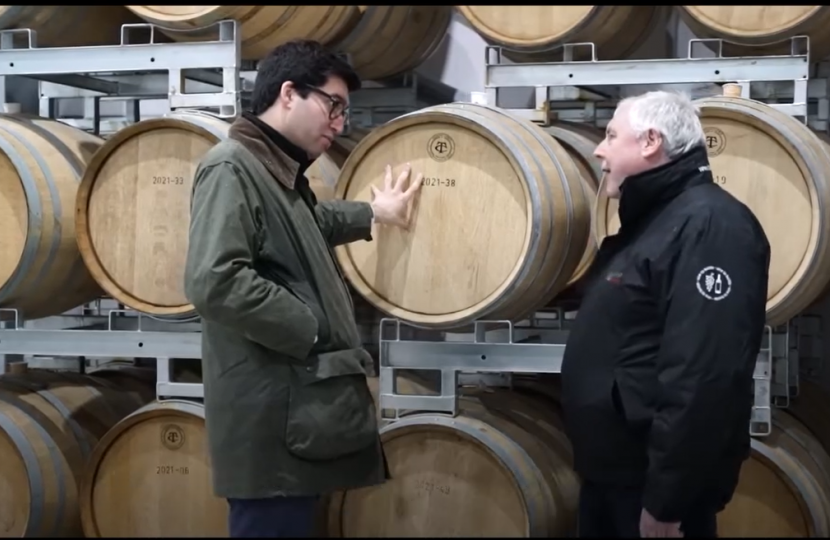 Ranil and a manufacturer in front of wine barrels 