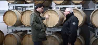 Ranil and a manufacturer in front of wine barrels 